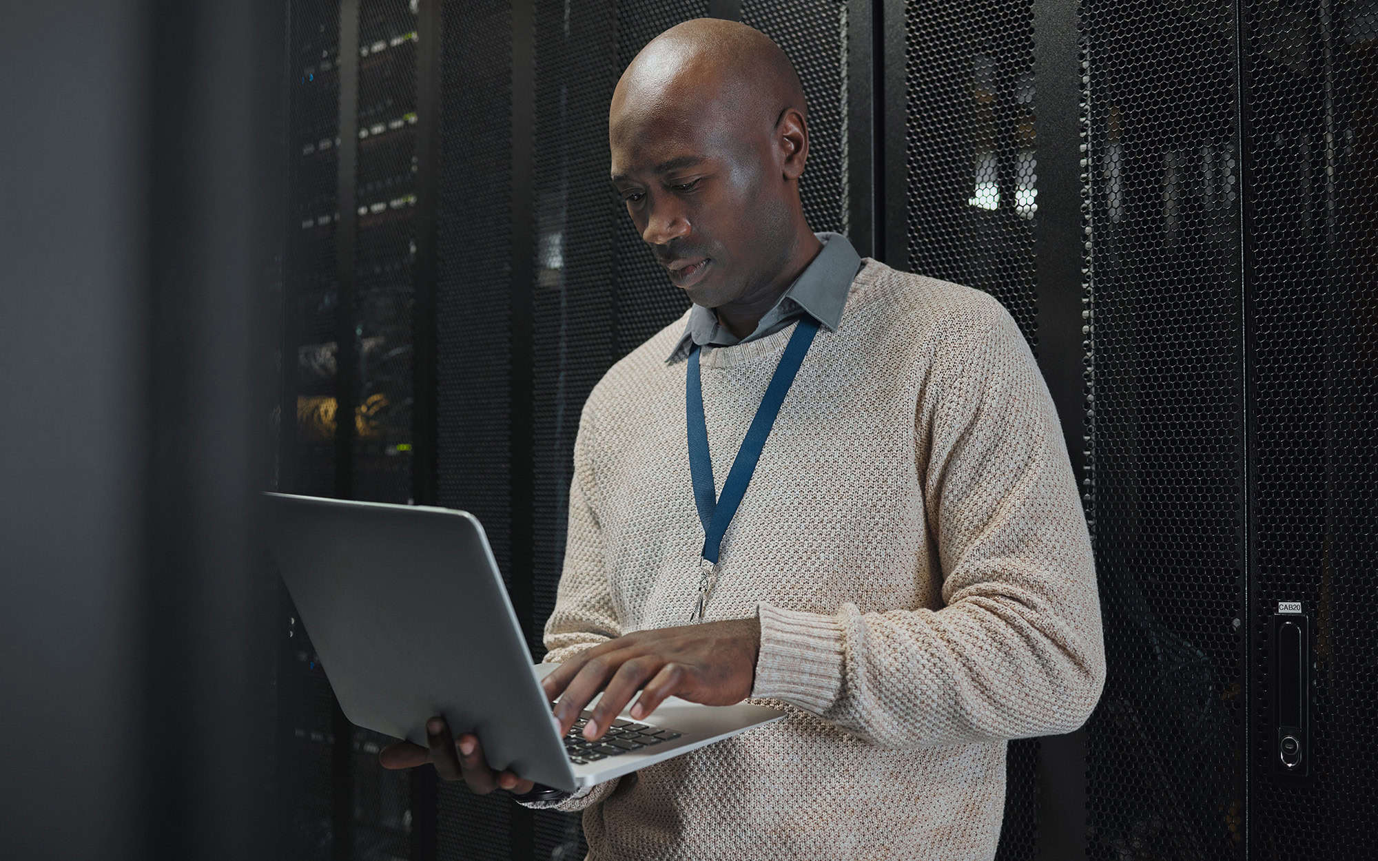 Man Holding Laptop in Front of Server Racks
