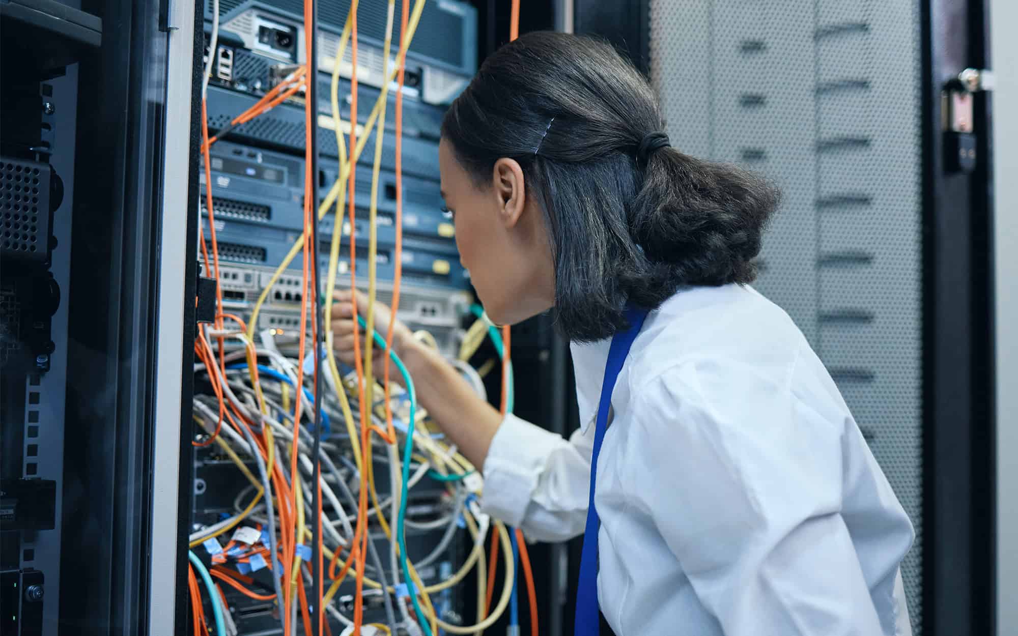Woman Connecting Cables in Back of Server Rack