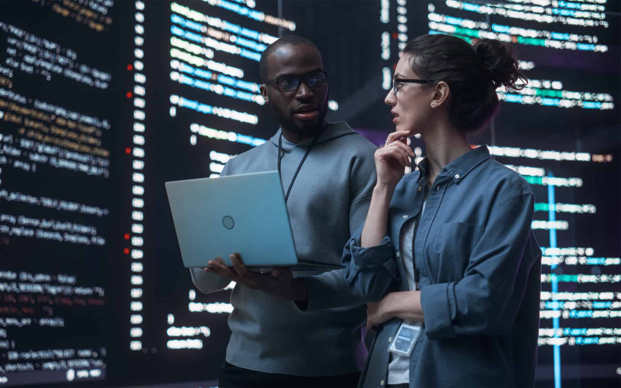 IT Technicians in Room with Large Monitors Discussing Data