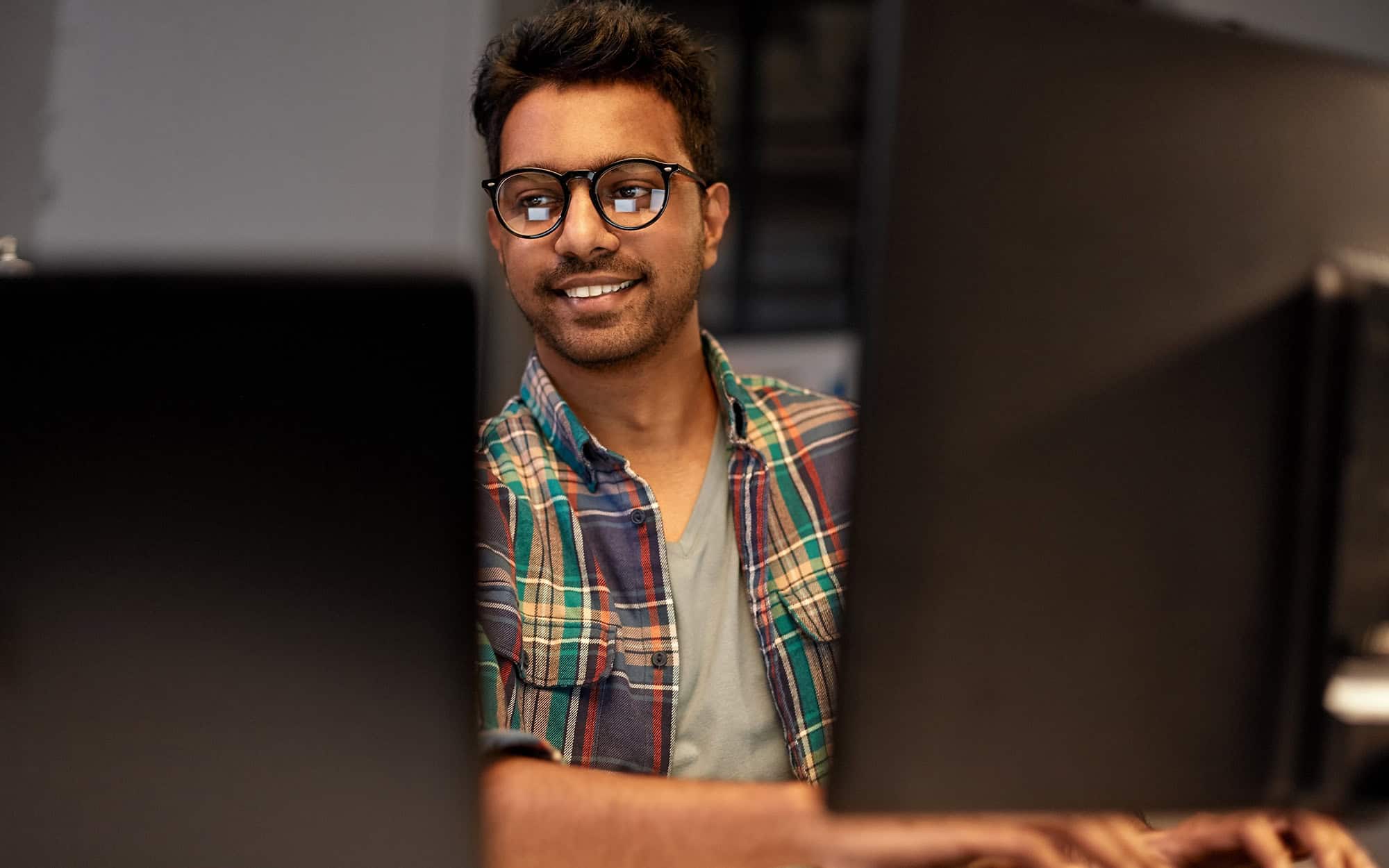 Smiling IT Technician Using Multiple Monitors to Work