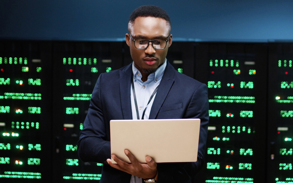 technician in a suit holding a laptop in a data center